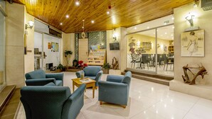 A spacious lobby with a wooden ceiling, comfortable seating, a coffee shop, and a large window with a view of the interior. - Alborada Aparthotel (Sliema)