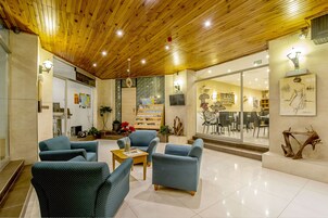 Un vestíbulo espacioso con techo de madera, asientos cómodos, una cafetería y un gran ventanal con vistas al interior.