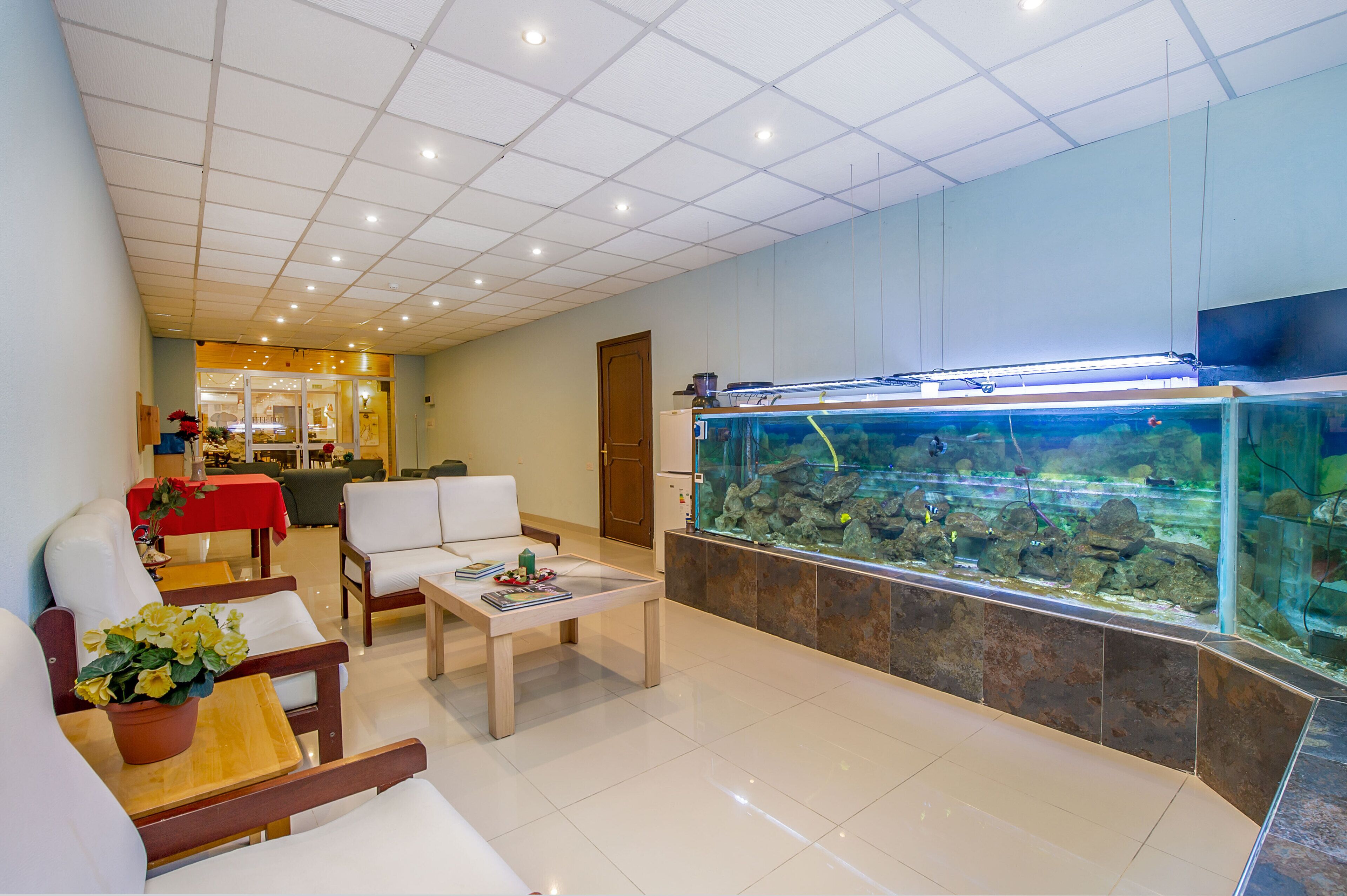 Un hall de hotel con un acuario grande, una zona de estar y un mostrador de recepción.