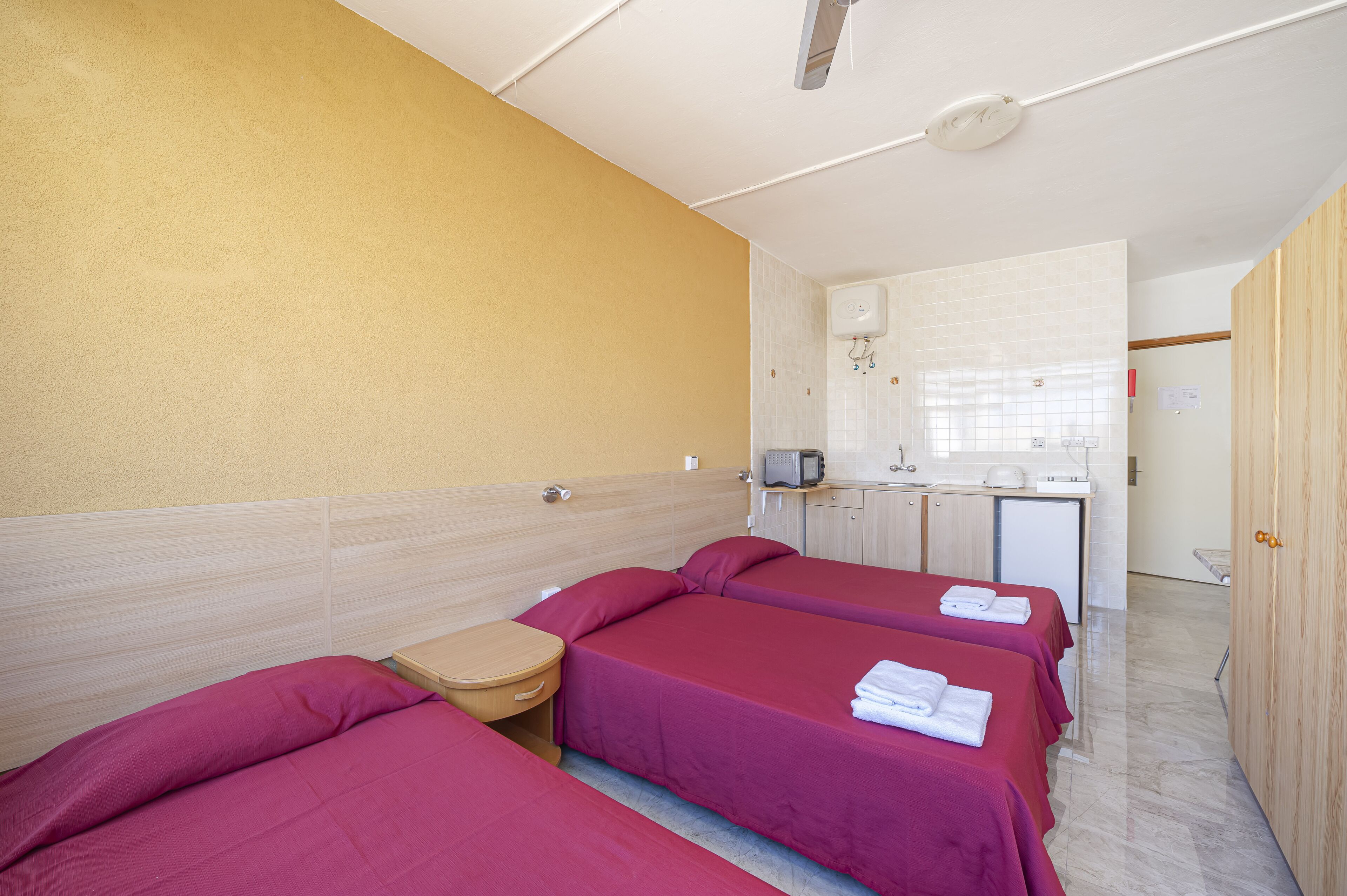 Ein Hotelzimmer mit zwei Betten, einem kleinen Schreibtisch, einer Mikrowelle und einem Waschbecken.