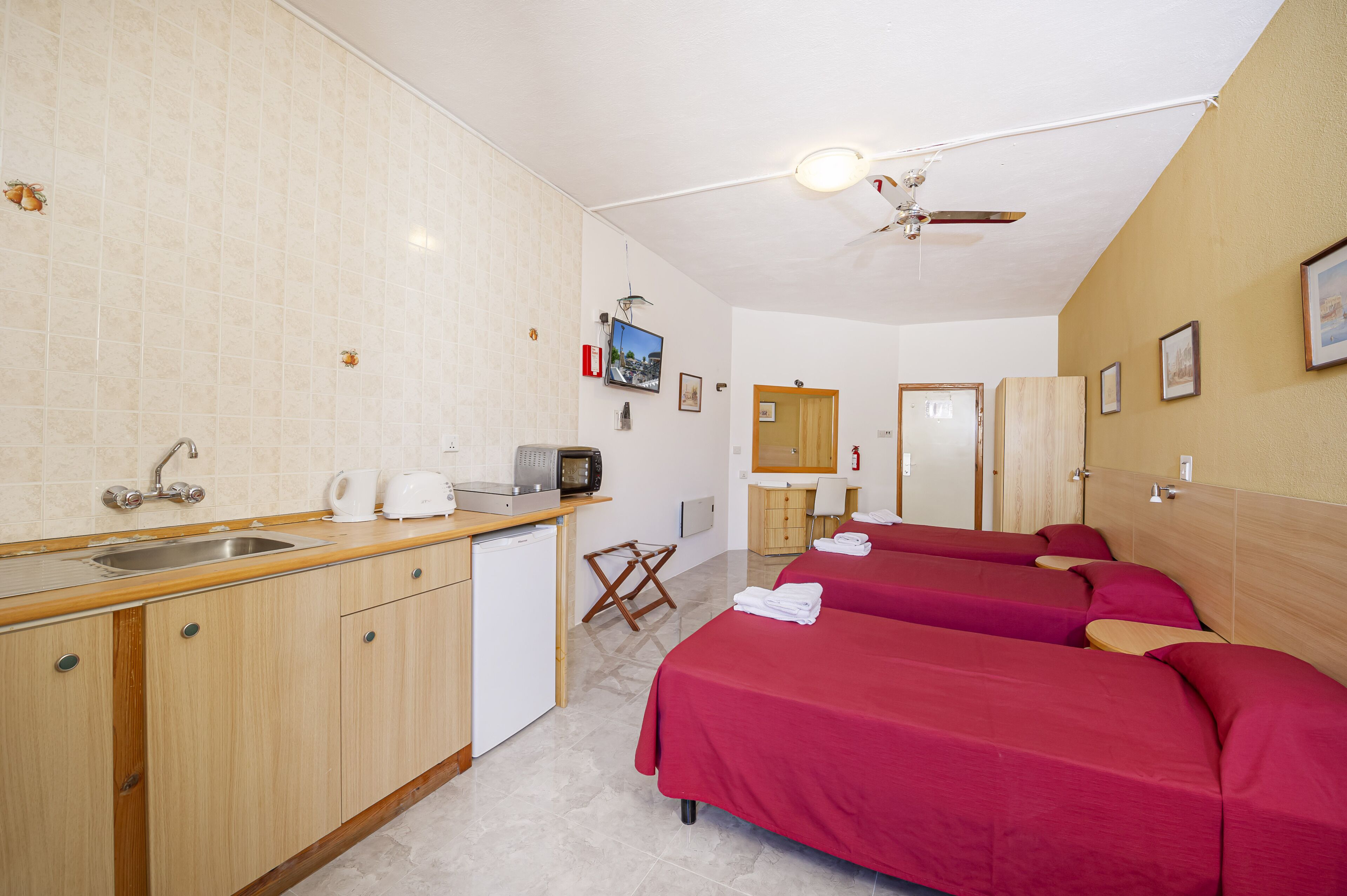 Ein Hotelzimmer mit Küchenzeile, einem Bett und einem Deckenventilator.