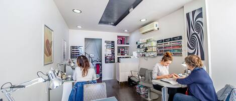 A modern salon interior with a reception desk, seating area, and various beauty products on shelves.