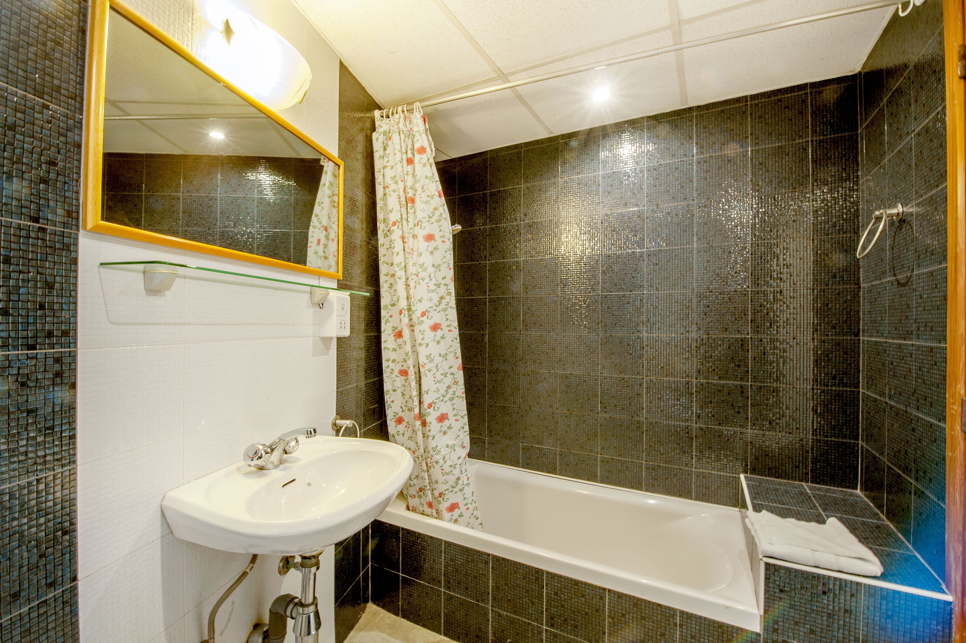 Ein Badezimmer mit einem weißen Waschbecken, einem Spiegel und einer Badewanne.