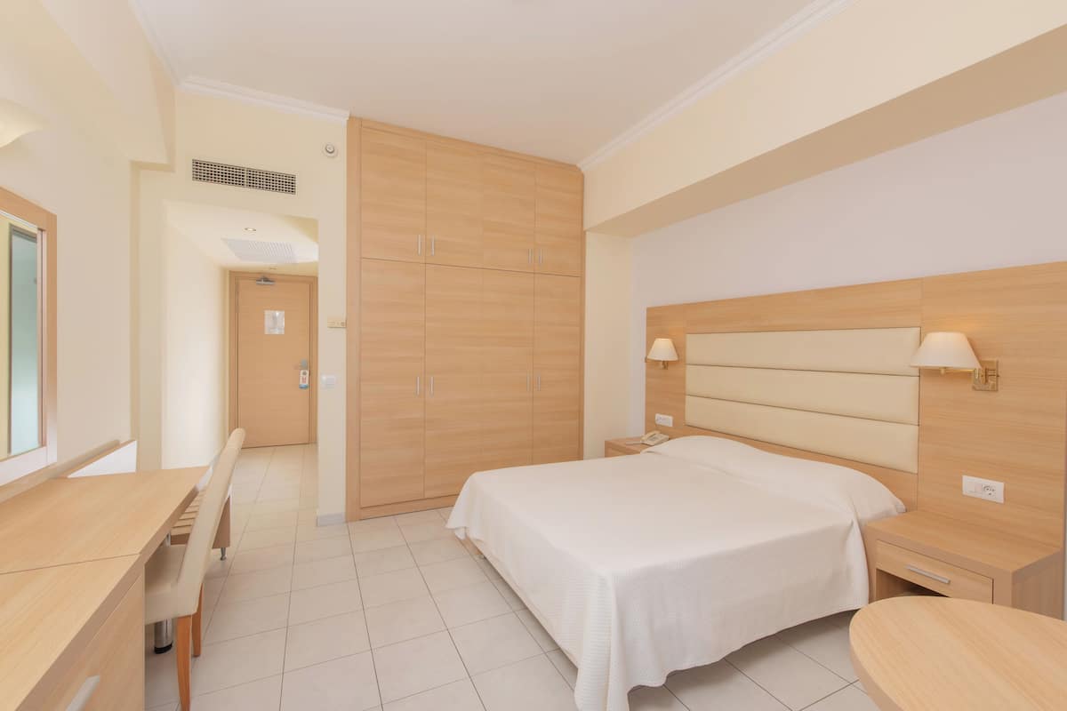 Una habitación de hotel con una cama, mesitas de noche, un escritorio y una silla.