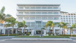Un hôtel à plusieurs étages, doté d’une architecture moderne, avec des balcons, de grandes fenêtres et une entrée principale.