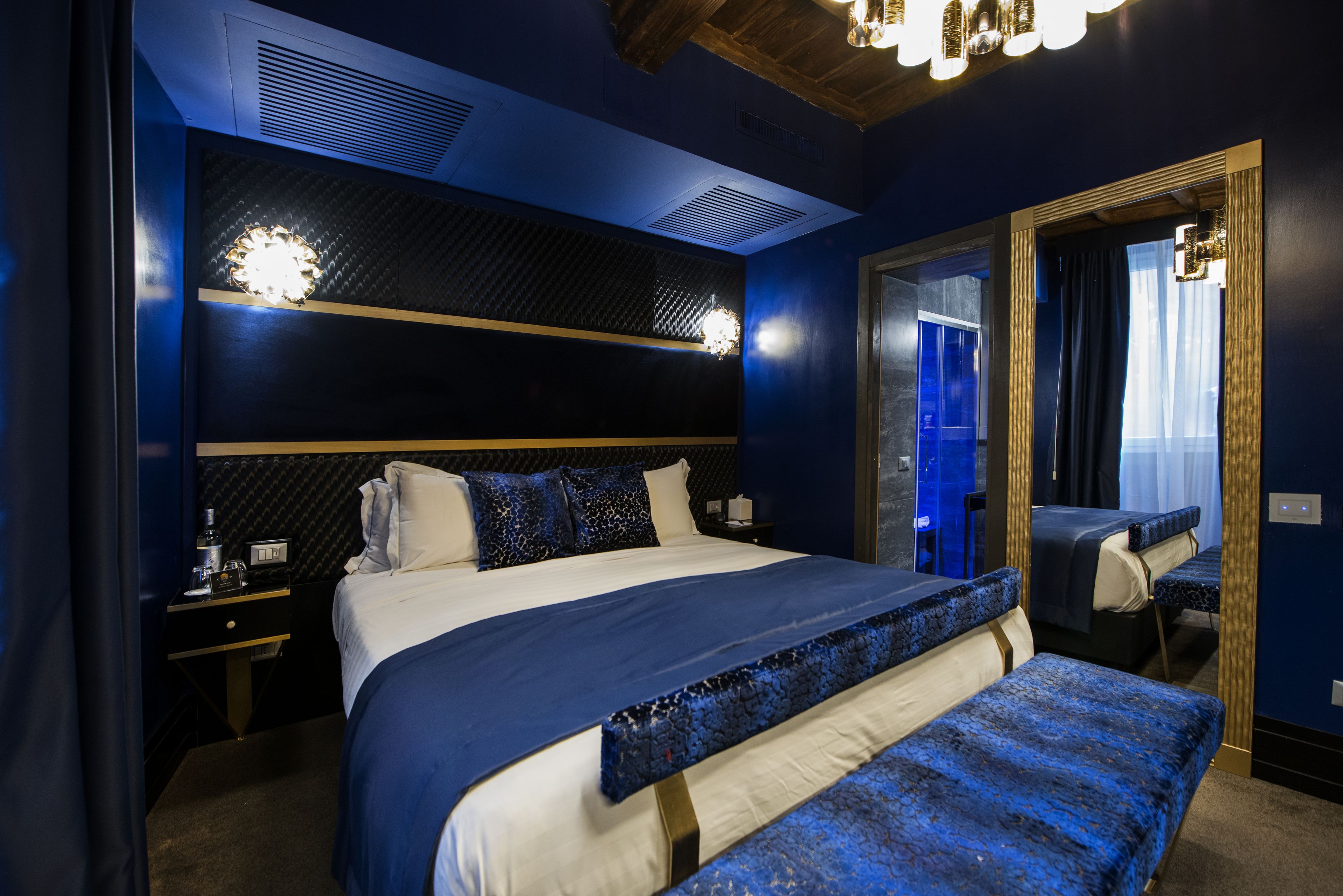 Una camera d'albergo moderna con un letto grande, un comodino, uno specchio e vista all'esterno.