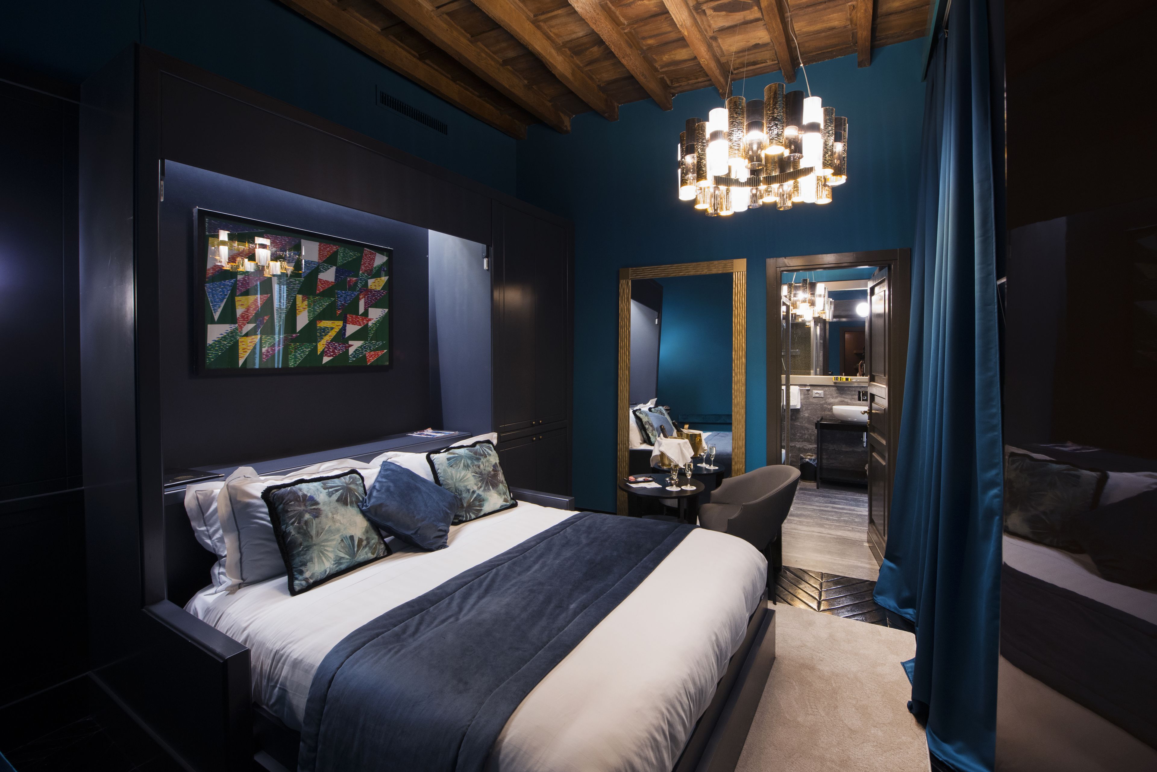 Ein modernes Schlafzimmer mit einem großen Bett, einer Chandelüster und einem Spiegel.
