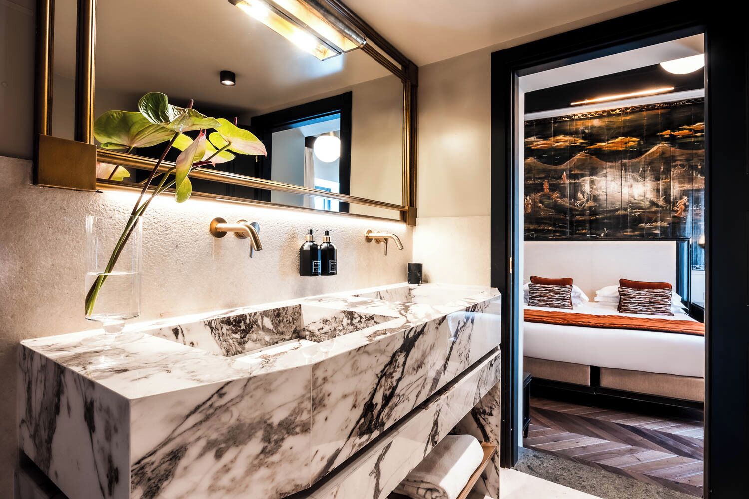 Un bagno con un lavabo in marmo, un grande specchio e una pianta.