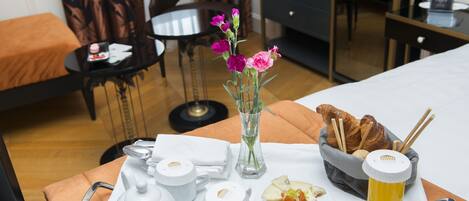 A breakfast tray with croissants, cheese, ham, and a glass of juice on a hotel room table.