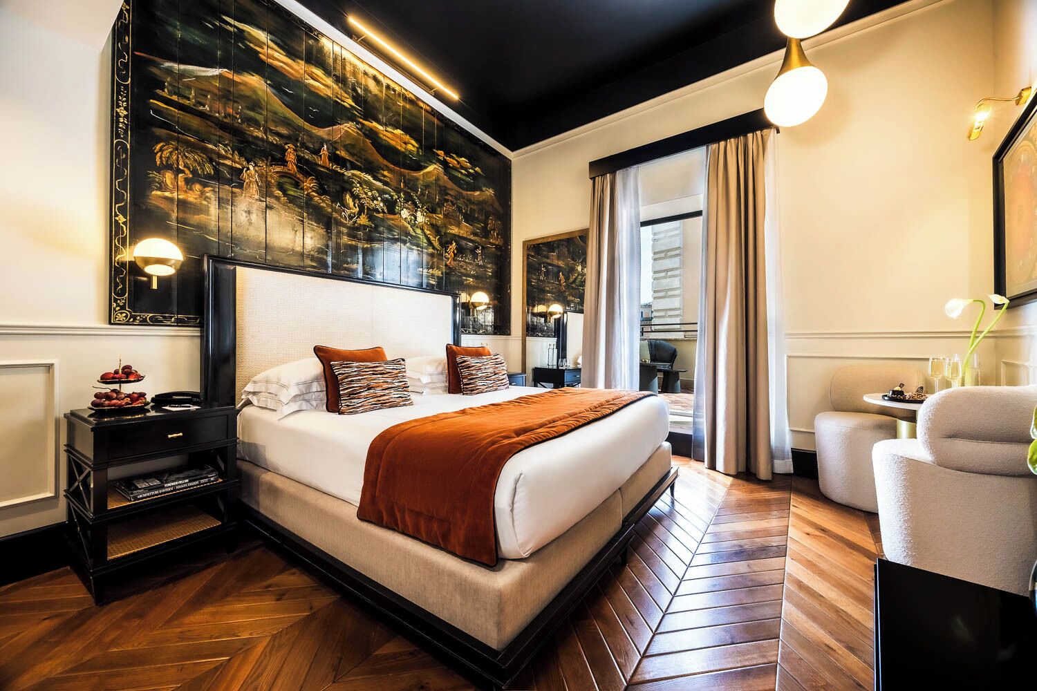 A hotel room with a large bed, a nightstand, a desk, a chair, and a large window.
