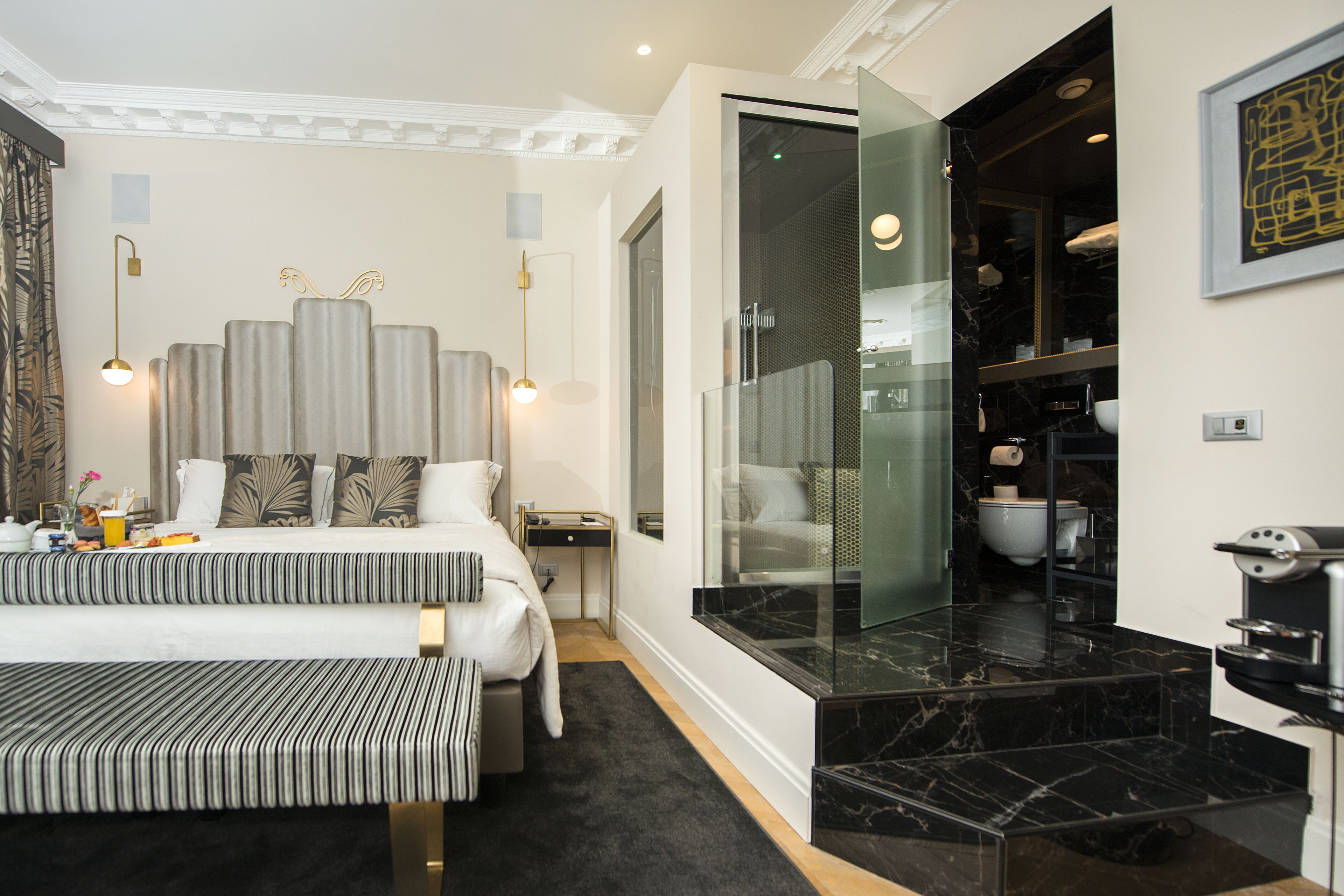 Une chambre d’hôtel moderne dotée d’un grand lit, d’un coin salon et d’une salle de bain séparée avec une paroi en verre.