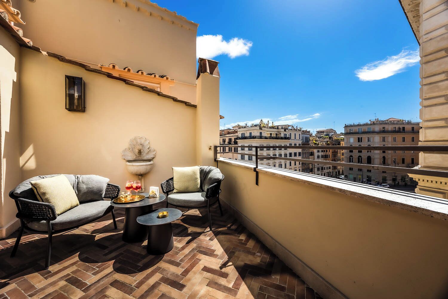 A balcony with two chairs, a small table, and a decorative fountain.