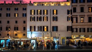 Un edificio a più piani con file di negozi al piano terra, tra cui una pizzeria e un bar.