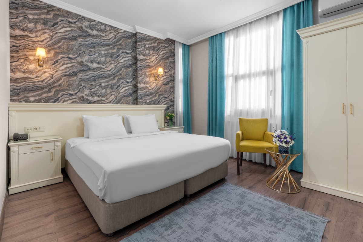 A hotel room with a bed, a nightstand, a chair, a wardrobe, and a marble-patterned wall.