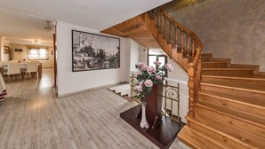 A spacious living area with a wooden staircase, a dining area, and a large framed picture on the wall.