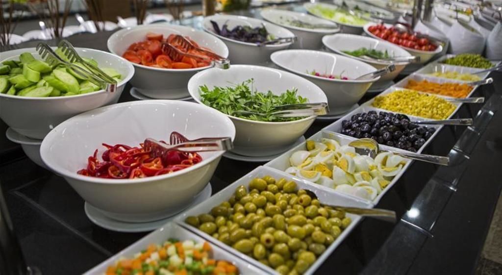 A buffet with various food options including vegetables, fruits, and eggs.