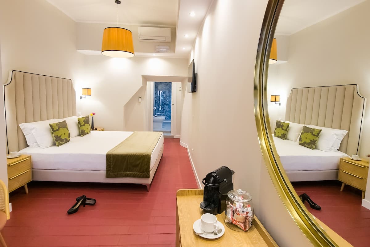A hotel room with two beds, a coffee maker, a tray with a cup and snacks, and a large mirror.