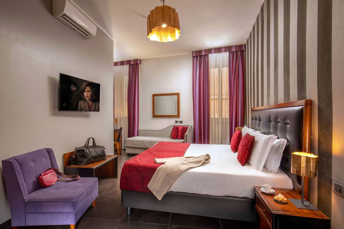 A hotel room with a bed, a sofa, a desk, and a chair.