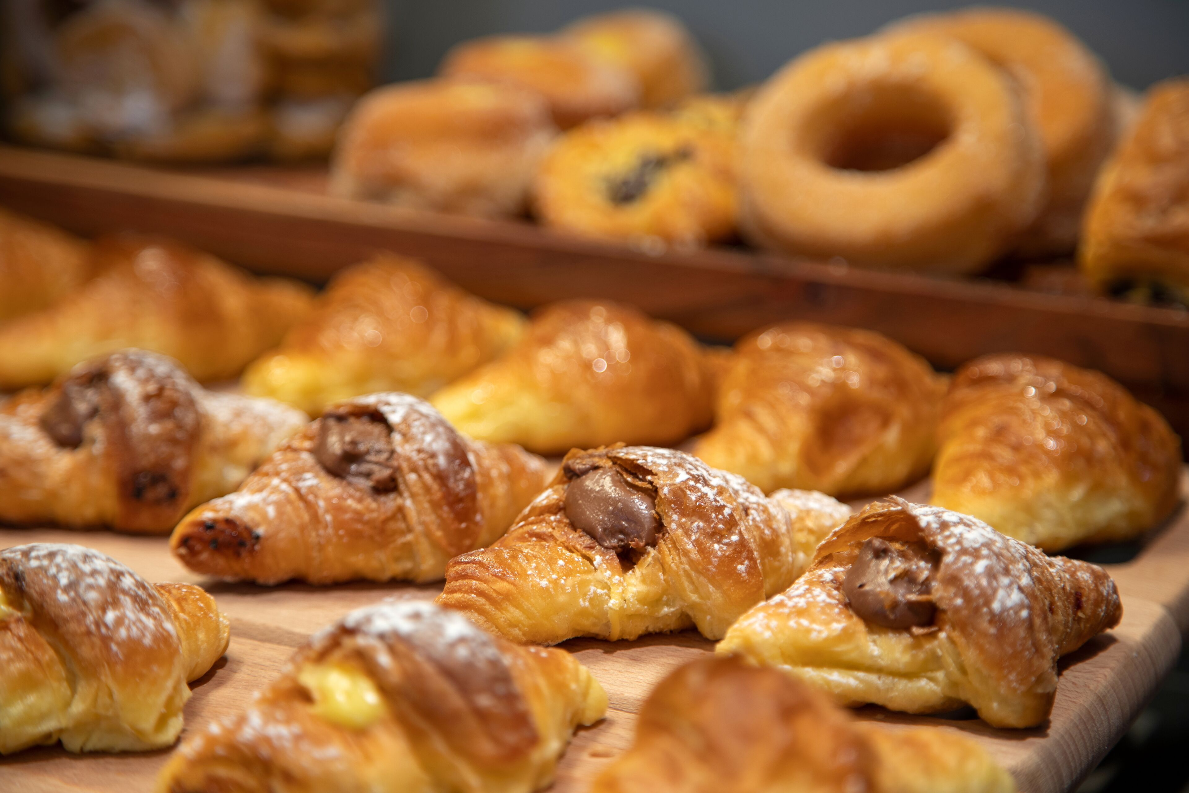 Une variété de viennoiseries, notamment des croissants et des beignets, présentées sur une planche en bois.