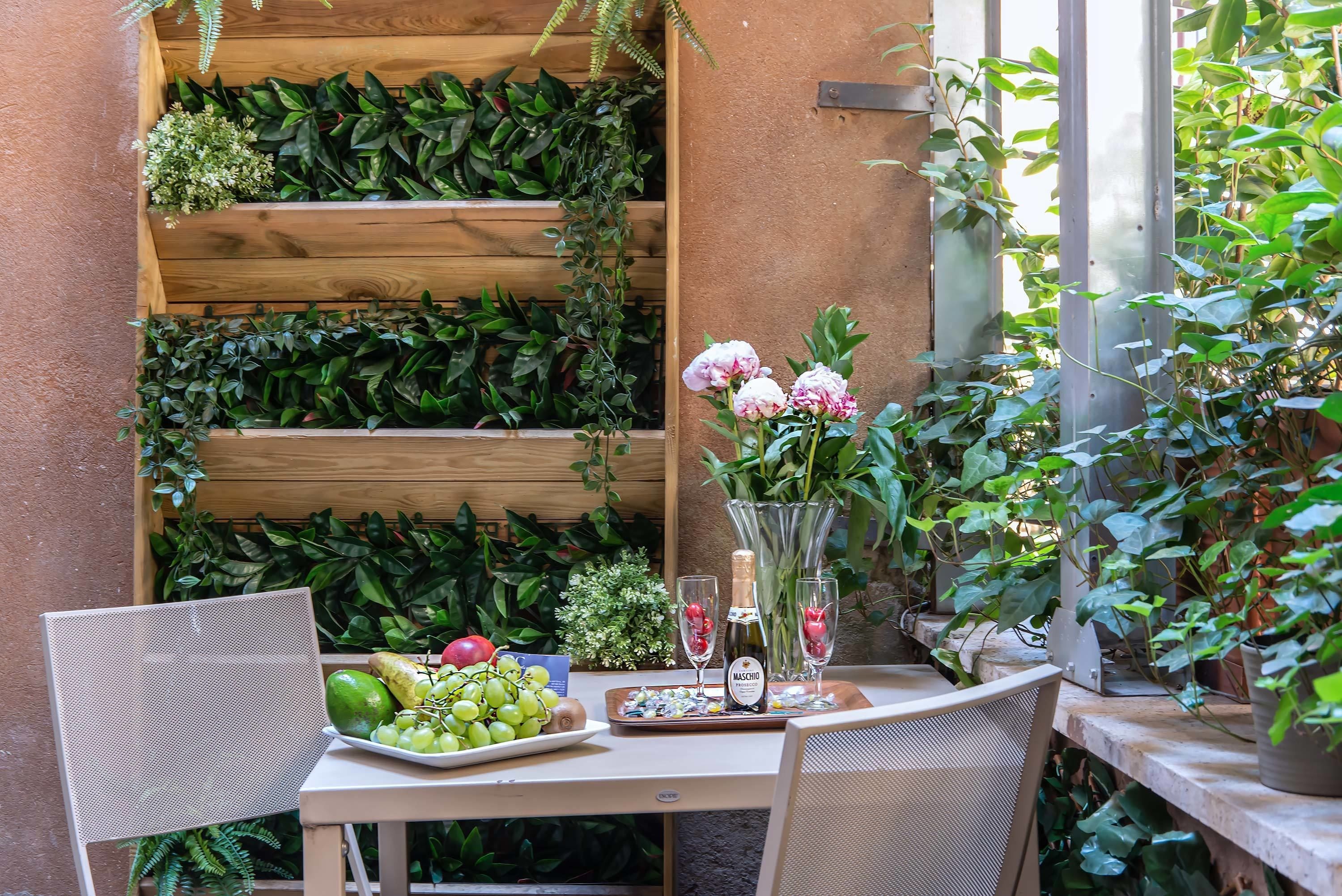 A table with a plate of grapes, a bottle of wine, and a vase with flowers.