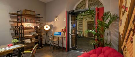 A cozy room with a red bean bag, a desk with a computer, a bookshelf, and a door leading to a balcony.