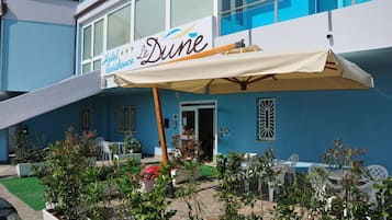 Hotel chamado 'Hotel Residence Le Dune' com área externa para sentar e plantas em vasos.
