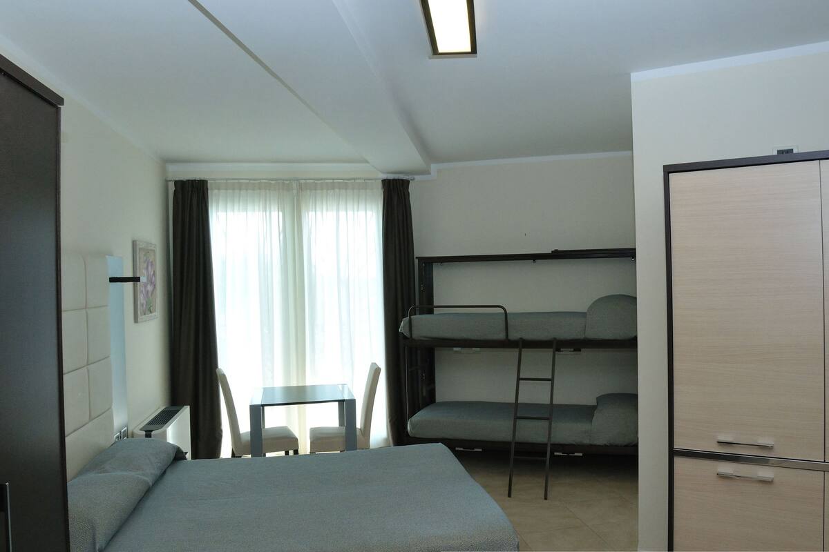 A compact room with a bunk bed, a desk, and a chair.