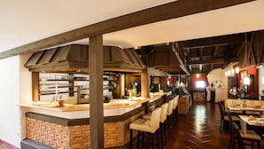 A bar area with a brick fireplace, wooden beams, and a tiled floor.