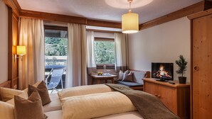 A hotel room with two beds, a television, a small table with a plant, and a view of the outdoors.