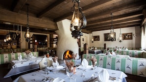 A restaurant with wooden beams, hanging light fixtures, and tables set for dining.