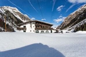 A two-story building with a sloped roof, surrounded by snow-covered mountains and clear skies.