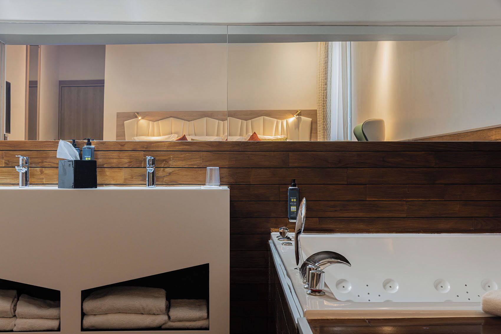 A modern bathroom with a wooden vanity, a large mirror, and a bathtub.