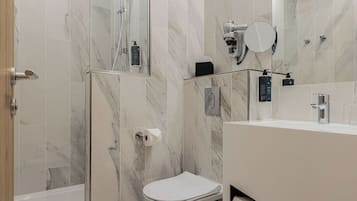 Une salle de bain moderne équipée d’une douche, de toilettes et d’un meuble-lavabo.