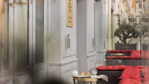 A room with a glass door, a small table with a book and a cup, and a red sofa. - Best Western Plus Hotel Comedie Saint-Roch (Montpellier)