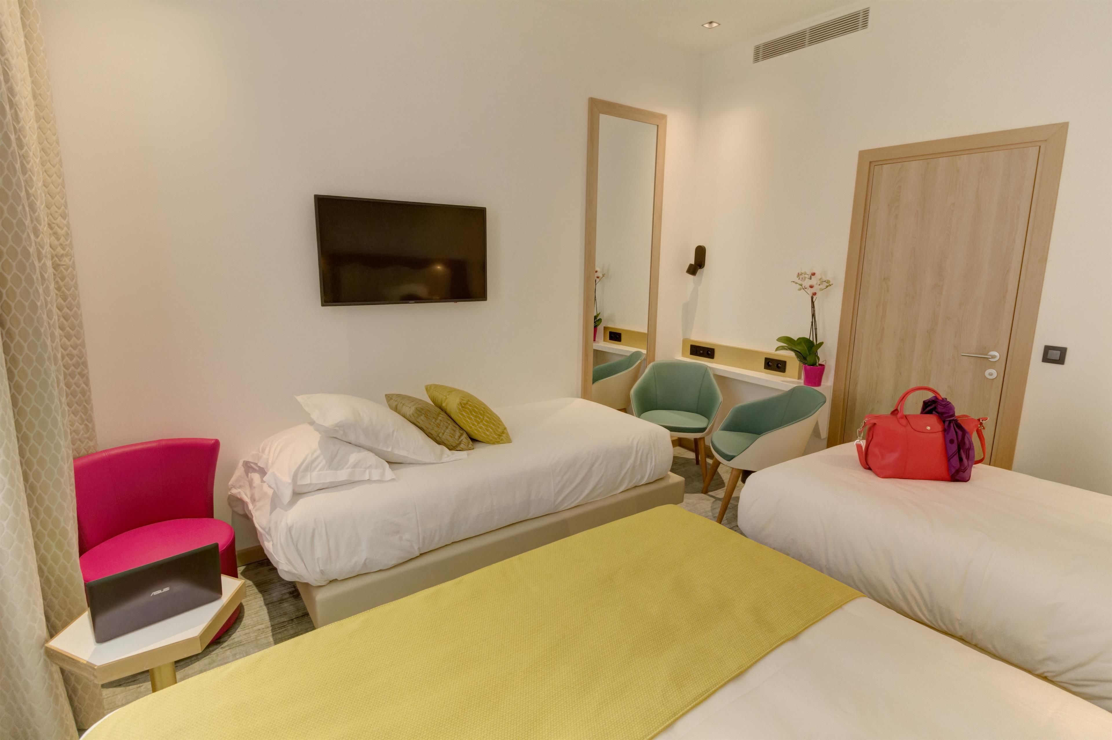 A hotel room with two beds, a desk, a chair, a TV, and a wardrobe.