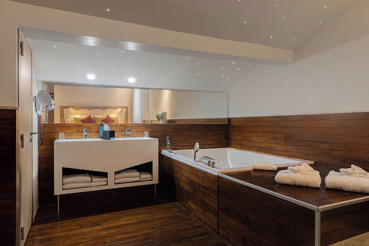 A modern bathroom with a wooden vanity, a large mirror, and a bathtub.