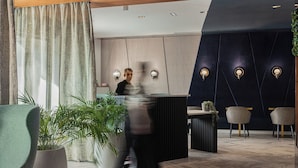 A modern reception area with a wooden reception desk, a large potted plant, and two chairs. - Best Western Plus Hotel Comedie Saint-Roch (Montpellier)