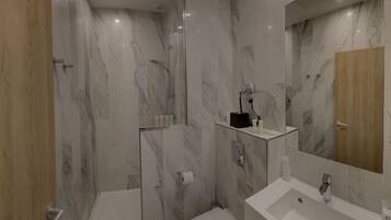 A modern bathroom with a shower, toilet, and sink.