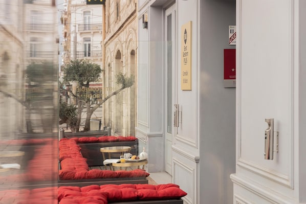 A hotel corridor with red upholstered seating, a small table with a cup and saucer, and a sign indicating 'Best Western Plus' accommodation.