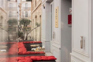 Pasillo de hotel con asientos tapizados en rojo, una mesa pequeña con una taza y platillo, y un letrero que indica el alojamiento 'Best Western Plus'.