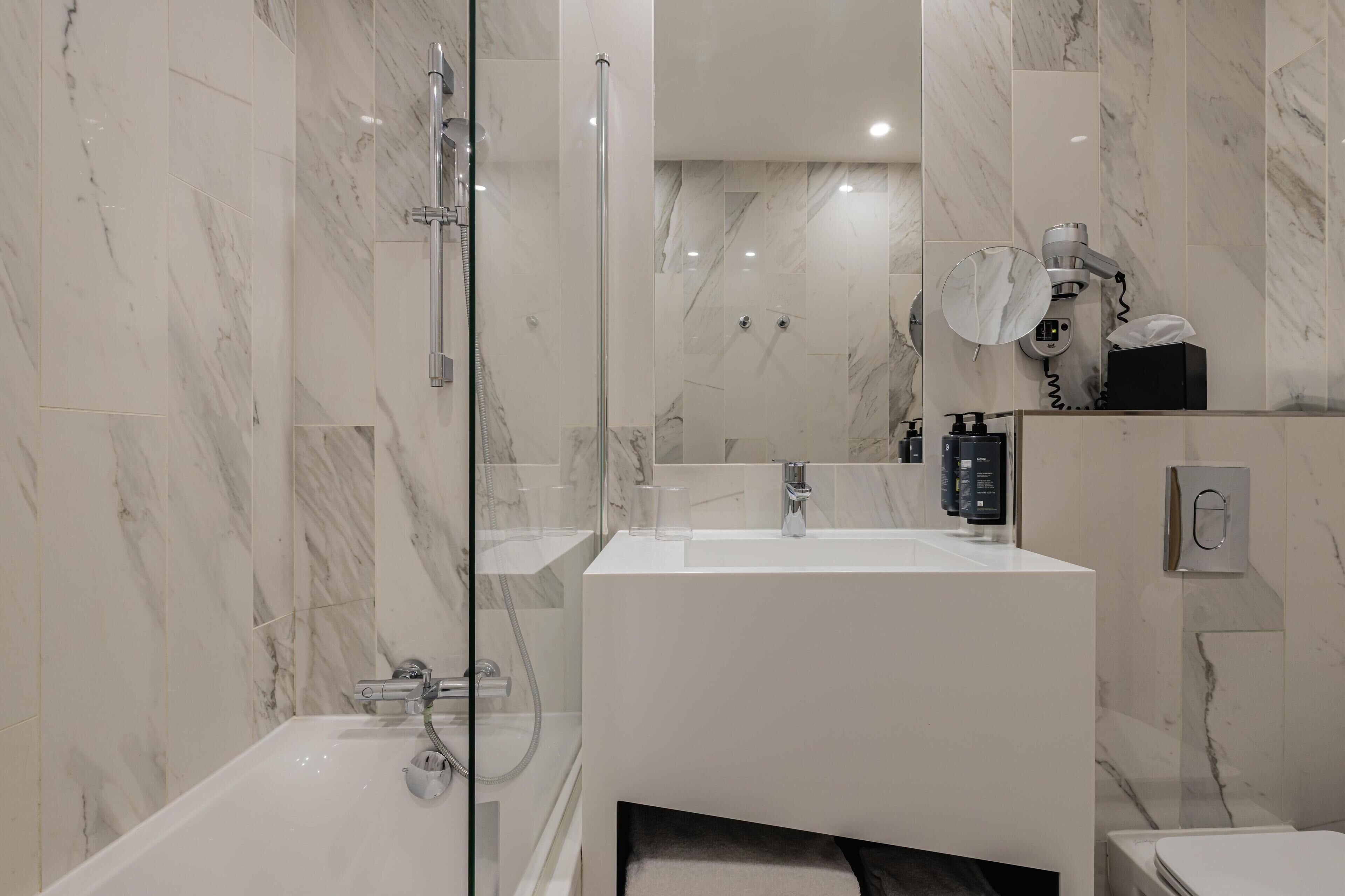 A modern bathroom with a glass-enclosed shower, a white sink, and a mirror.