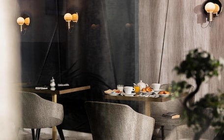 A modern dining area with a table set for breakfast, including croissants and orange juice.