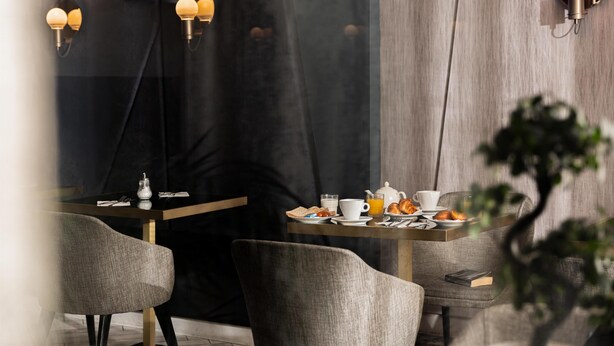 A modern dining area with a table set for breakfast, including croissants and orange juice. - Best Western Plus Hotel Comedie Saint-Roch (Montpellier)