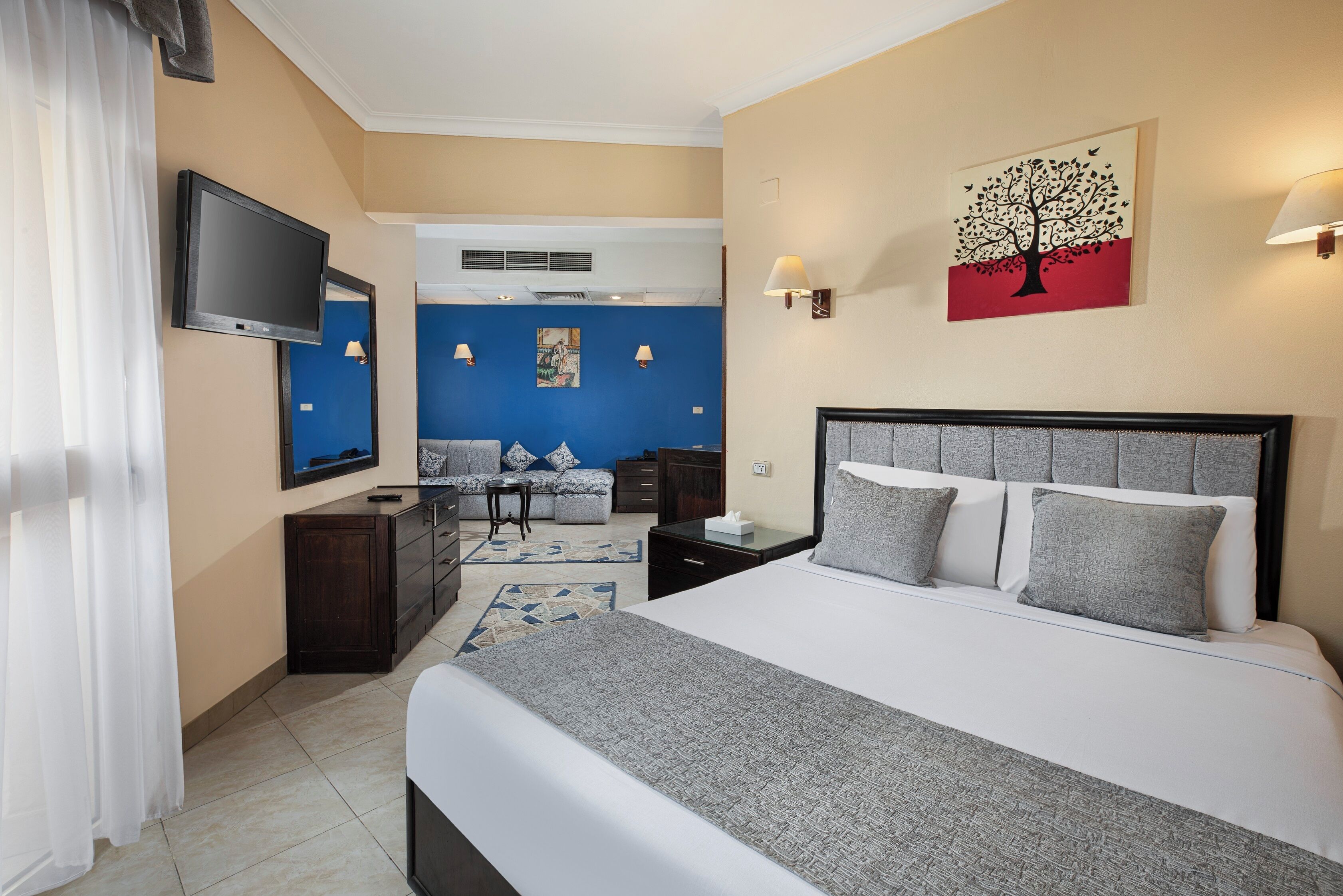 A hotel room with a bed, a TV, a desk, a chair, and a sofa.