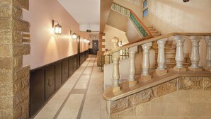 Un couloir d’hôtel avec un mur en pierre sur la gauche, un escalier en bois sur la droite et un panneau indiquant le numéro de l’étage.