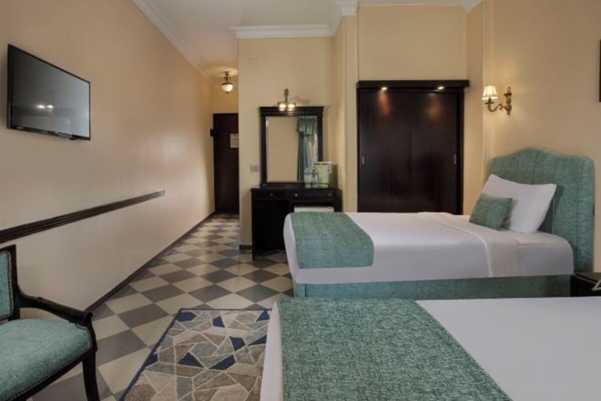 A hotel room with a bed, a desk, a chair, a television, and a wardrobe.