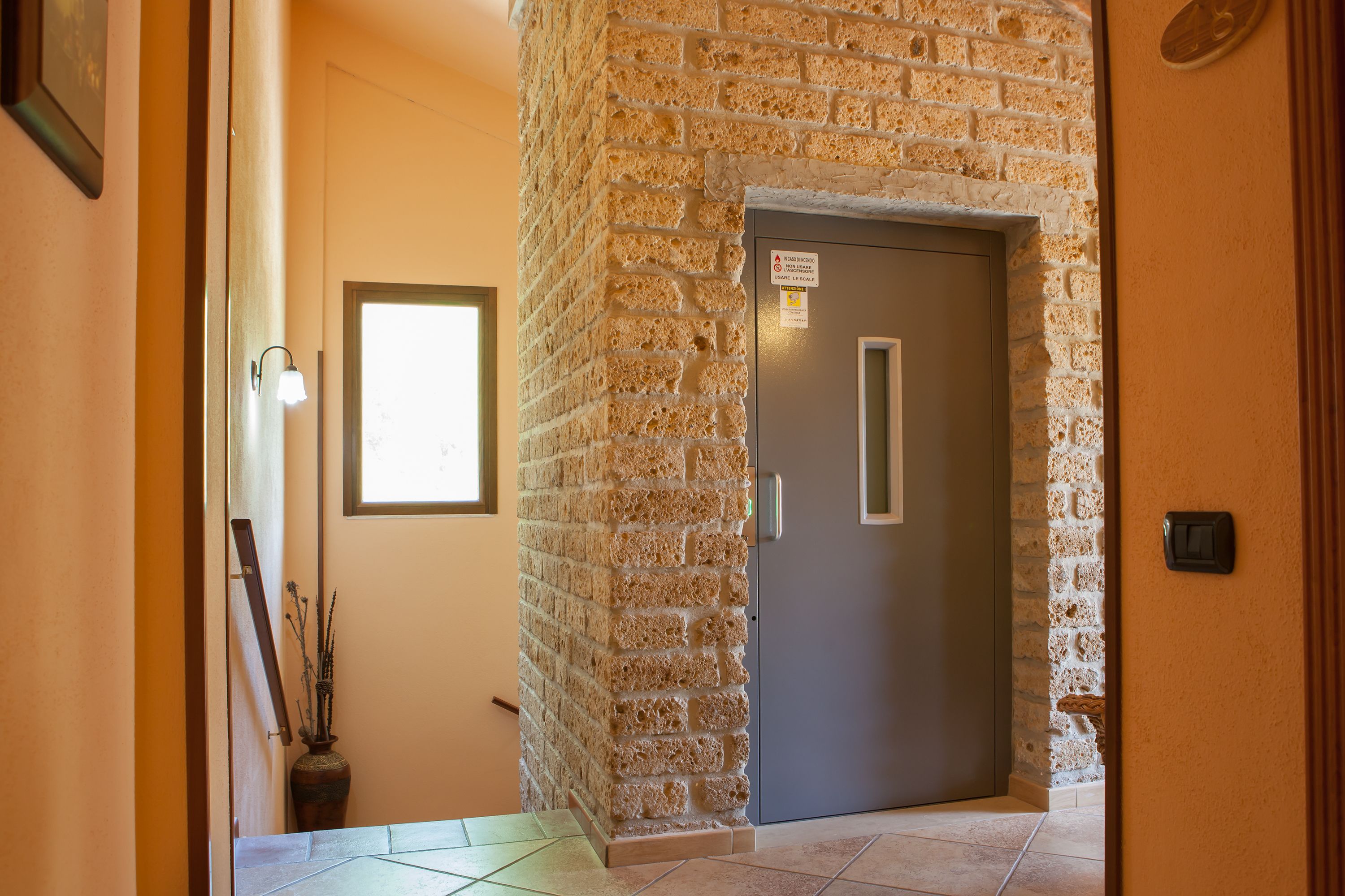A hallway with a stone wall, a door, and a window.