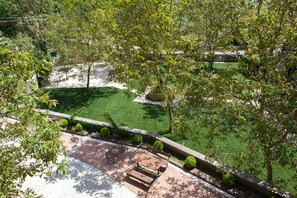 A patio area with a wooden table and benches, surrounded by a brick pathway and trimmed bushes. - Agriturismo La Sfruscià (San Gregorio Magno)