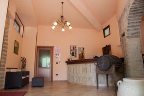 A reception area with a wooden counter, a large vase, and a chandelier. - Agriturismo La Sfruscià (San Gregorio Magno)
