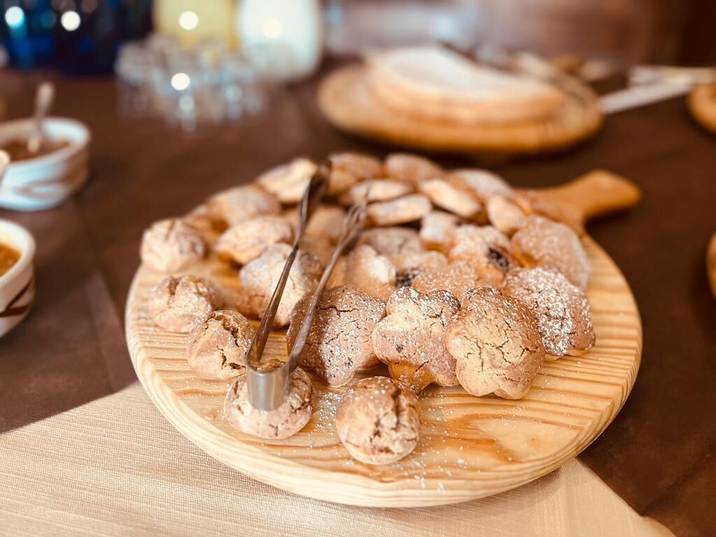 A wooden serving board with pastries and a pair of tongs.
